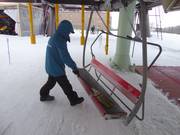 Le siège est balayé de la neige à l’embarquement à l’aide d’un balai.